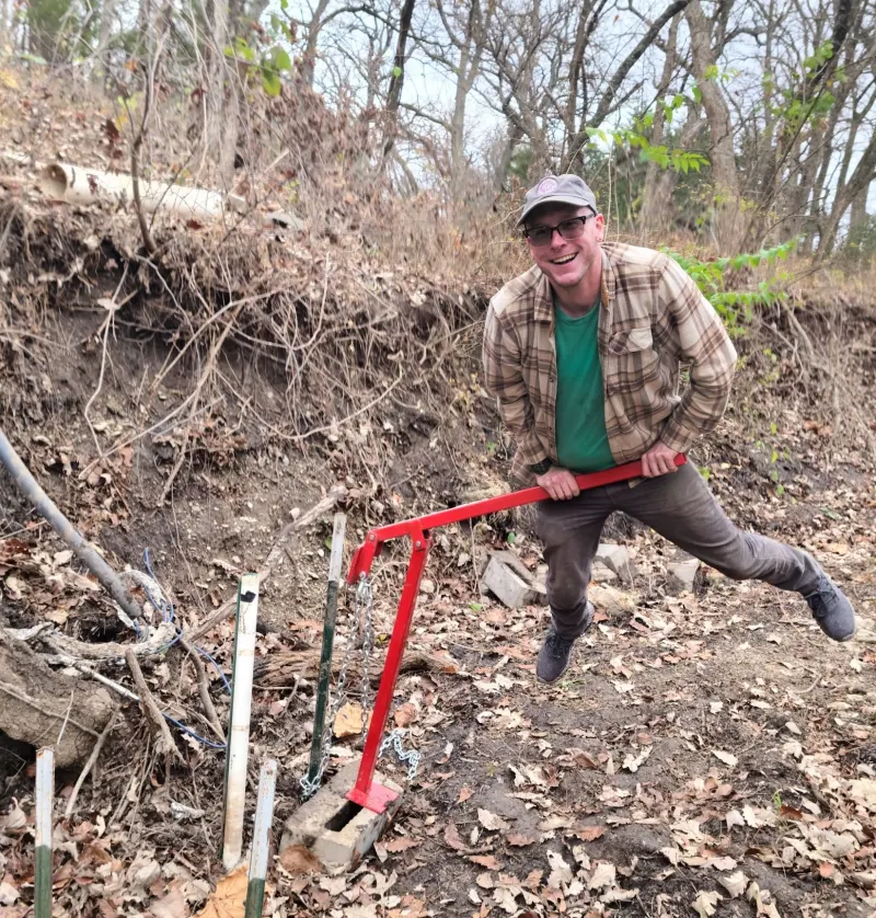 Connor with a post puller removing t-post from Shane Creek